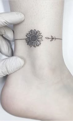 a sunflower tattoo on the ankle with an arrow in front of it that is attached to