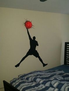 a basketball player jumping up into the air with a red ball in his hand on top of a bed