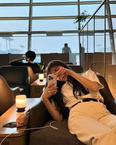 a woman laying on top of a couch next to a table holding a cell phone