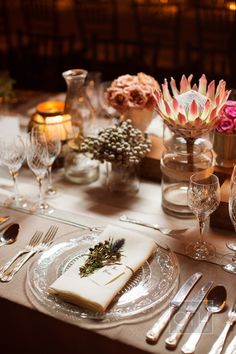 the table is set with silverware and flowers