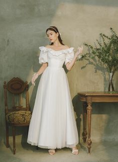 a woman in a white dress standing next to a table