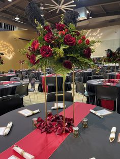 a centerpiece with red roses and greenery sits on top of a round table