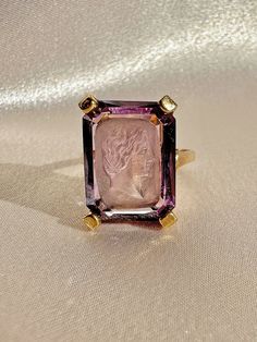 "Antique 10k yellow gold amethyst intaglio ring of a woman's portrait from the early 20th century. Great antique condition Size: 7.25 resizable** Weight: 5.3 grams Band: 1.4 mm, 6.8 mm (height) Amethyst: 16.0 mm x 12.0 mm rectangle cut Hallmarks: 10k, makers mark \"ROMANY\" Please note, vintage and antique jewelry may come with imperfections commensurate of their age. To see more photos and videos of this piece, visit our Instagram: www.instagram.com/23carat" Intaglio Ring, Dress Ring, Dress Rings, Female Portrait, Early 20th Century, Makers Mark, Rings Statement, Antique Jewelry, Statement Rings