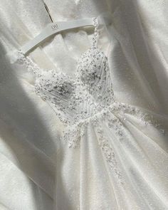 a white wedding dress with beading on the back and neckline, hanging from a hanger