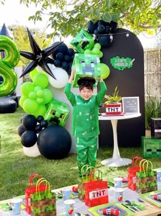 a young boy dressed in green holding up a box