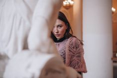 a woman standing in front of a statue with her hand up to the side and looking into the camera