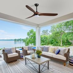 a living room filled with furniture and a large window covered in glass doors looking out onto the water