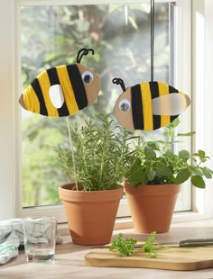 two planters with fake bees on them sitting next to each other in front of a window