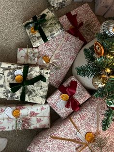 several wrapped presents sitting next to a christmas tree