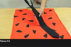 someone is cutting out an orange piece of paper with black tape on top of it