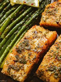 grilled salmon and asparagus on a plate with lemon wedges in the background