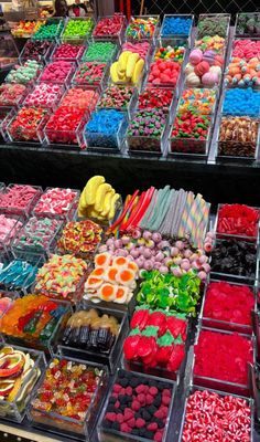 many different types of fruits and vegetables are displayed in trays on the table for sale