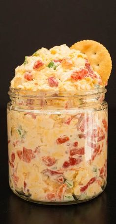 a jar filled with food sitting on top of a black table next to a cookie