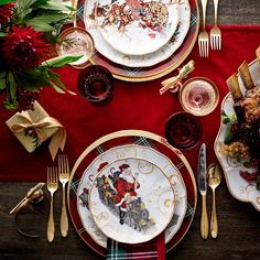 a table set for christmas with plates, silverware and red napkins on it