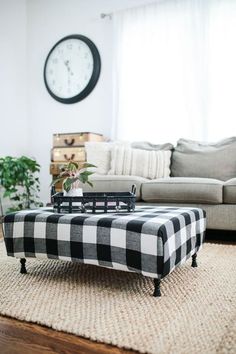 a black and white checkered ottoman sitting on top of a rug in front of a couch