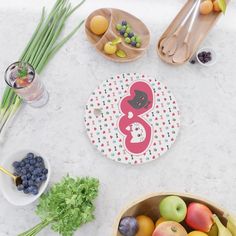 there are fruits and vegetables on the table next to bowls of fruit, spoons and utensils