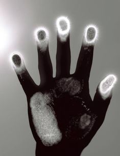 a person's hand with glowing fingers and thumbnails in black and white