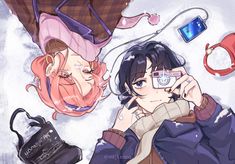 two people laying next to each other with cell phones on their heads and various accessories around them