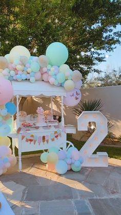 three women standing in front of a backdrop with balloons and teacups on it