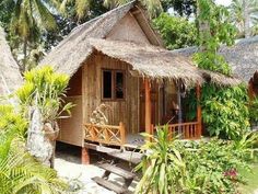 a small hut with thatched roof surrounded by greenery