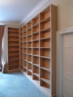 empty bookshelves in the corner of a room with blue carpet and tan walls