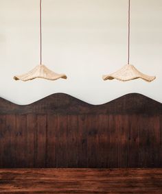 two lamps hanging over a wooden headboard in a room with white walls and wood paneling