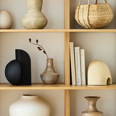 vases and books on shelves in a room with neutral colors, including black and white