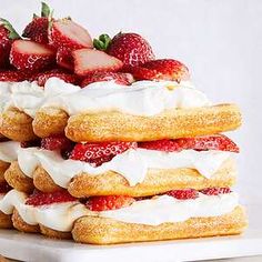 strawberry shortcakes stacked on top of each other with whipped cream and strawberries