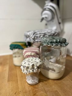 three jars filled with stuff sitting on top of a wooden table