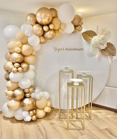 there is a large balloon arch in the middle of this room with gold and white balloons