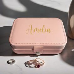 an open pink box with two rings in it and the word ameli next to it