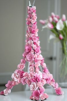 a pink flowered eiffel tower is shown in front of a vase with flowers