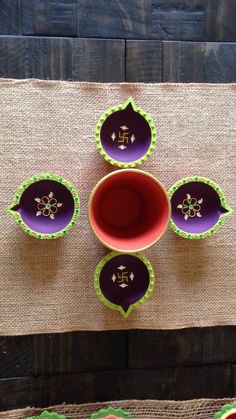 four purple and green dishes sitting next to each other on top of burlocks