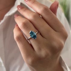 a woman's hand wearing a ring with an aqua blue stone on the side