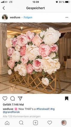 a bunch of flowers that are sitting on a wooden stand in front of a wall