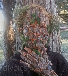 a man with his face covered in moss next to a tree