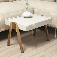 a white table with a vase on it in front of a couch and coffee table