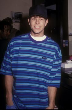 a young man wearing a blue and white striped shirt with a hat on his head