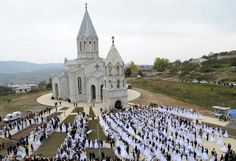 a large group of people standing in front of a church with white linens on the ground