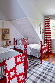 two beds in a room with red and white bedding on the walls, checkered rugs