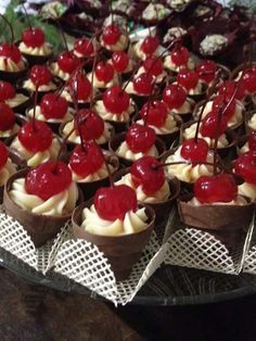 cupcakes with cherries and whipped cream are arranged on a platter at a party