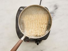 a frying pan filled with food on top of a stove burner next to a wooden spatula