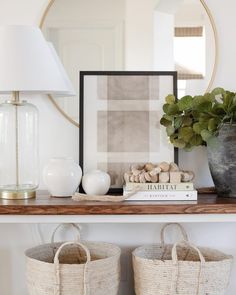 a shelf with two baskets, a lamp and a book on it in front of a mirror