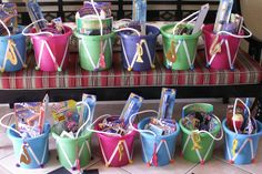 several buckets filled with candy sitting on top of a table next to a bench