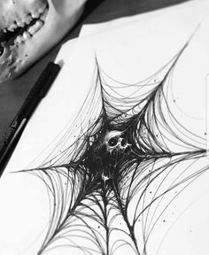 a drawing of a spider web on paper next to a pencil and crayon