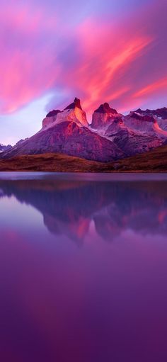 the mountain range is reflected in the still water at sunset, with pink and purple clouds