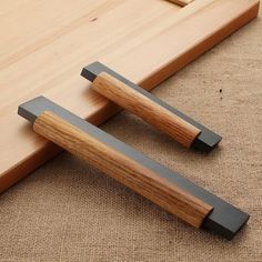 two pieces of wood sitting next to each other on a wooden floor with black handles