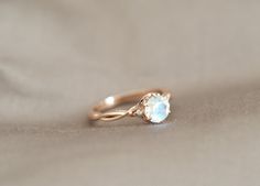 a gold ring with a blue stone on it's side sitting on a beige cloth