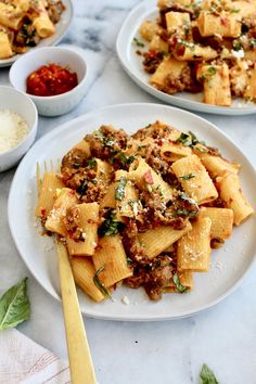 three plates of pasta with meat and sauces on the table next to bowls of rice