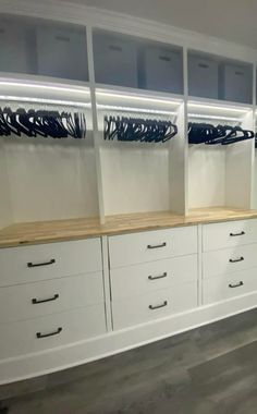 an empty walk in closet with white cabinets and drawers